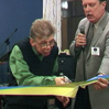 Jan Norinder holding holding an inauguration ribbon an another person cutting it.
