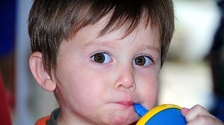 Ett barn som dricker ur en mugg med sugrör.