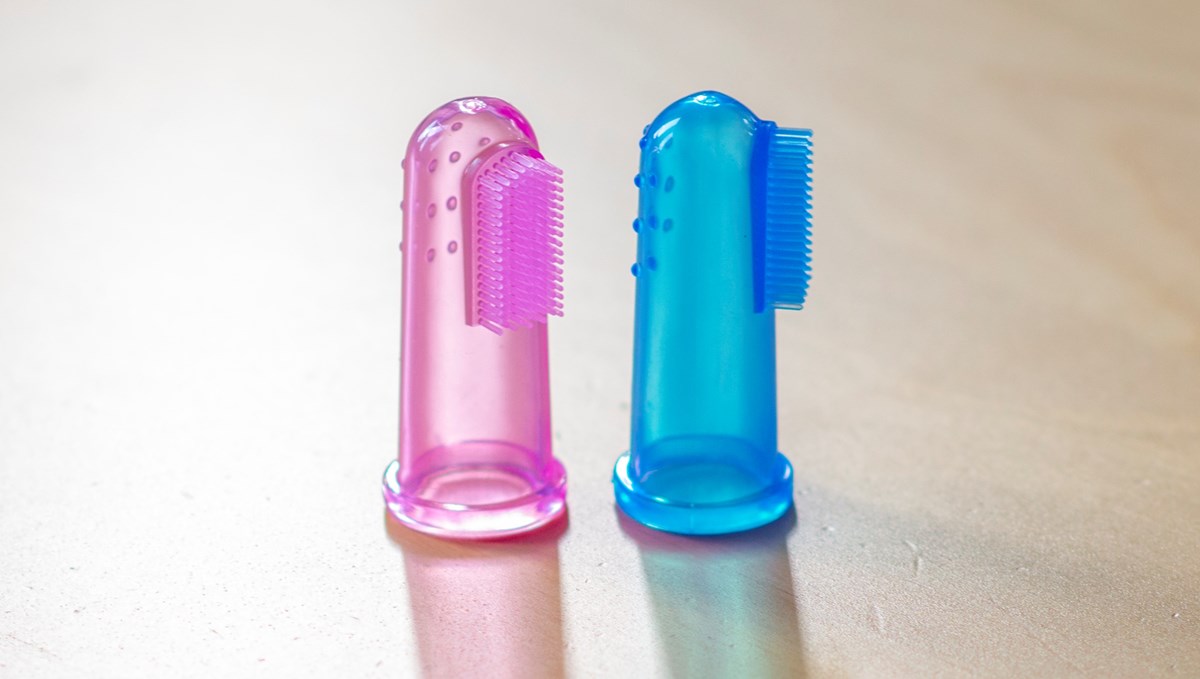 Två fingerborstar. Den vänstra i rosa, den högra i blå. Båda genomskinliga som man sätter på fingret. De har borstar på halva sidan.